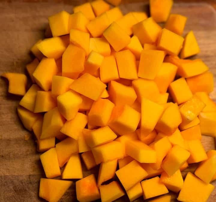 A cutting board with diced butternut squash