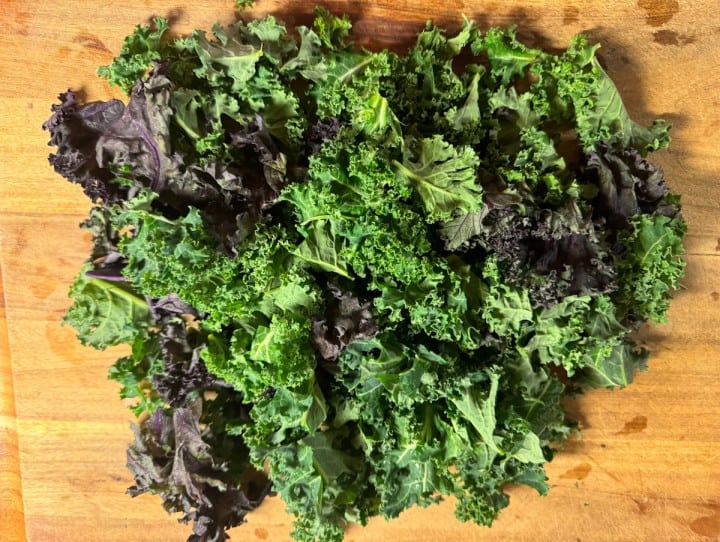 A cutting board with roughly chopped curly kale