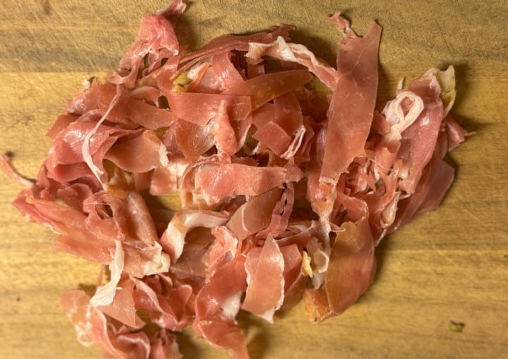 A cutting board with sliced proscuitto