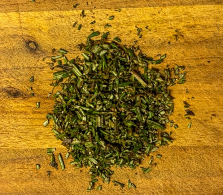 A cutting board with finely chopped rosemary
